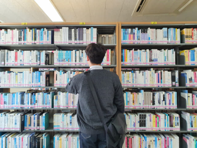 경남대 학생이 대학 도서관에서 책을 살펴보고 있다.