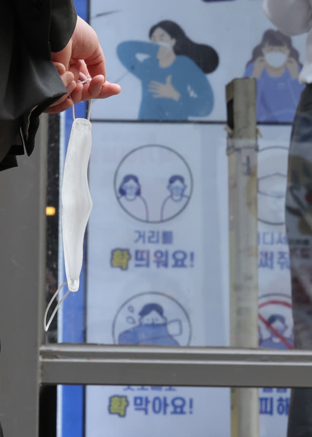22일 서울 시내에서 한 시민이 마스크를 손에 들고 있다. 정부는 실외 마스크 완전 해제를 포함한 방역 완화책을 이번주 내 발표할 계획이다. 연합뉴스