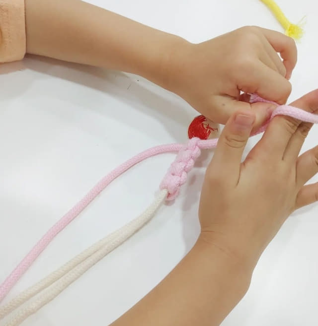 한 어린이가 마크라메 매듭을 만들고 있다.
