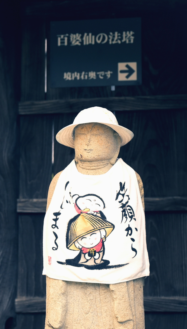 일본 아리타 보은사(호온지) 정문에 세워진 불상 뒤로 ‘백파선의 법탑(만료묘태도파의 비)’을 안내하는 문구가 적혀 있다.